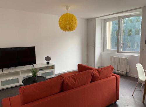 a living room with a red couch and a flat screen tv at Nationale Appart Hotel in Lille