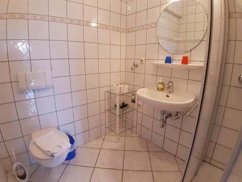 a white tiled bathroom with a toilet and a sink at Wellental in Breege