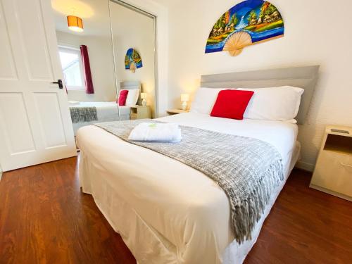 a bedroom with a large white bed with red pillows at Glasgow Green Park Home in Glasgow