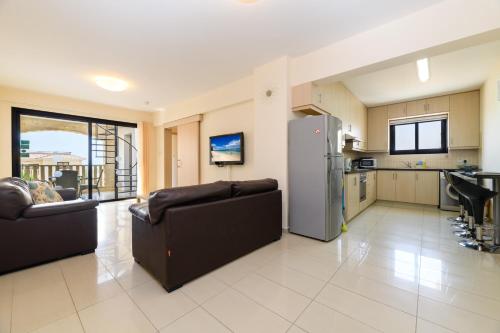 a kitchen and living room with two couches and a refrigerator at Blue Serenity Complex in Larnaka