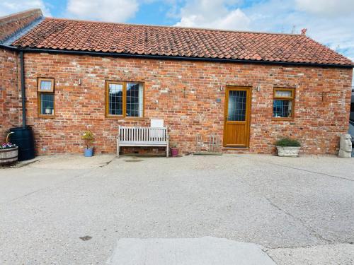 a brick building with a bench in front of it at Field Farm Holiday Cottages and Glamping in Anderby