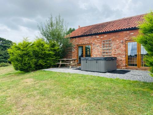 a brick house with a picnic table and a bench at Field Farm Holiday Cottages and Glamping in Anderby