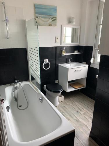 a bathroom with a tub and a toilet and a sink at Le cadran in Stella-Plage