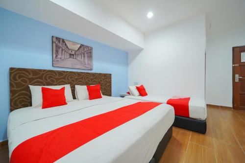 a hotel room with two beds with red pillows at JMA FERRINGHI BEACH HOTEL in Batu Ferringhi