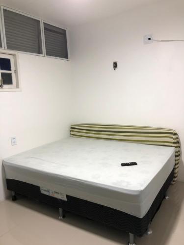uma cama num quarto com uma parede branca em Flat Bangalô 103 em Cabo Frio