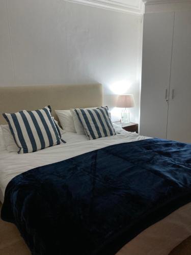 a bedroom with a large bed with blue and white pillows at 317 Neptunes Isle - Lagoon Beach in Cape Town
