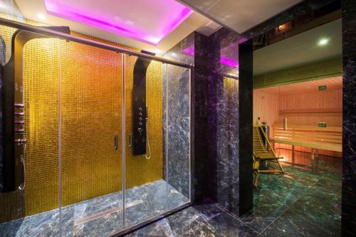 La salle de bains est pourvue d'une douche en verre avec des lumières violettes. dans l'établissement Aparthotel Baltic Spa, à Świnoujście