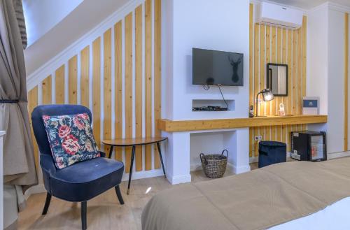 a bedroom with a bed and a chair and a tv at Hotel Tókert Szálloda és Étterem in Lillafüred