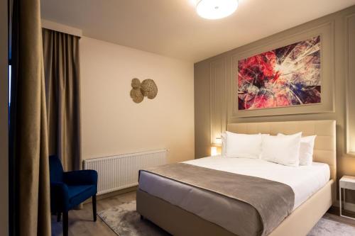 a hotel room with a bed and a blue chair at Aparthotel NOX in Cluj-Napoca