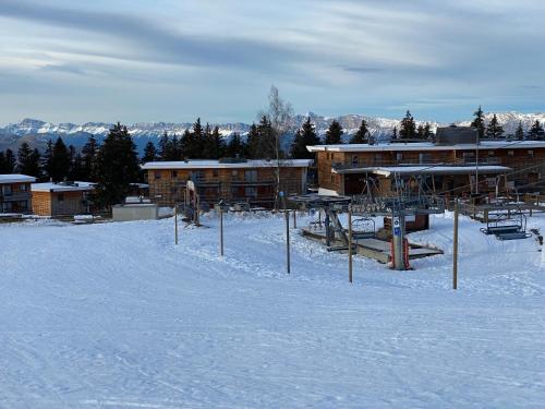 a person riding a snowboard in the snow in front of a building at apt 4/6 pers aux villages du Bachat chamrousse in Chamrousse