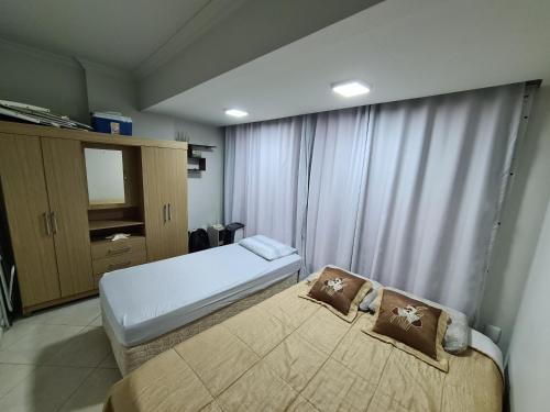 1 dormitorio con 2 camas y ventana en Apartamento na Av Atlantica com Ar Condicionado, en Balneário Camboriú