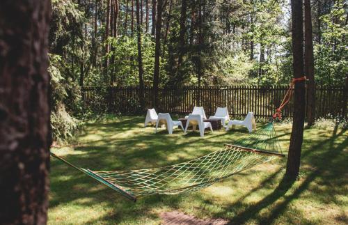a hammock in a yard with chairs and a fence at Jarzębinowa - Dom do wynajęcia na Podlasiu in Łuka