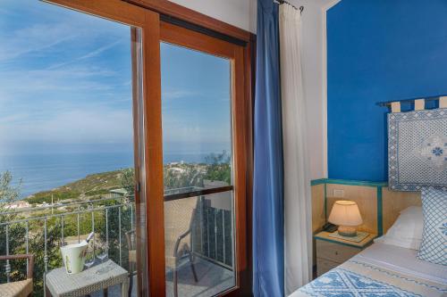 a bedroom with a window with a view of the ocean at Il Borgo BagaBaga - Exclusive Country Retreat in Castelsardo