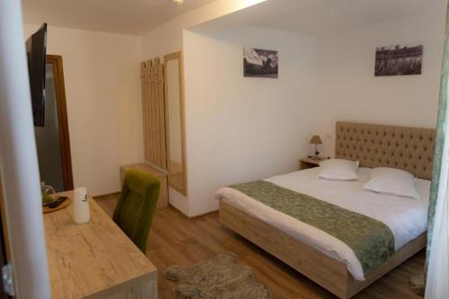 a bedroom with a bed and a desk and a television at La Helesteu in Lăzăreşti