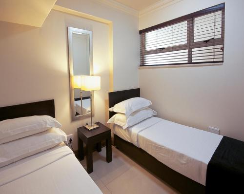 a hotel room with two beds and a window at Belaire Suites Hotel in Durban