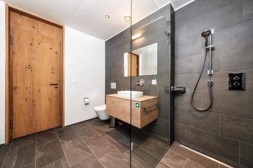 a bathroom with a shower and a sink and a toilet at Luxury Panorama apartment with AlpenGold Spa Access in Davos