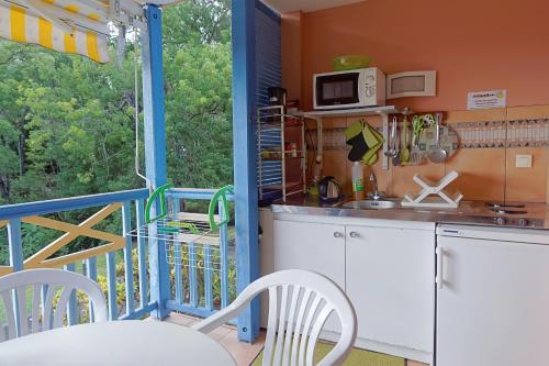 eine Küche mit einem Balkon mit einem Tisch und Stühlen in der Unterkunft Les Studios Kazado in Sainte-Anne