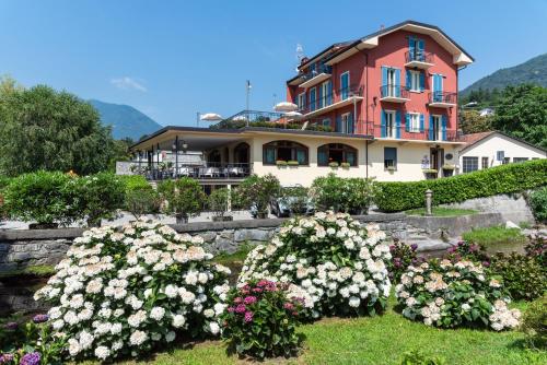 une grande maison avec des fleurs devant elle dans l'établissement Hotel Ristorante La Quartina, à Mergozzo