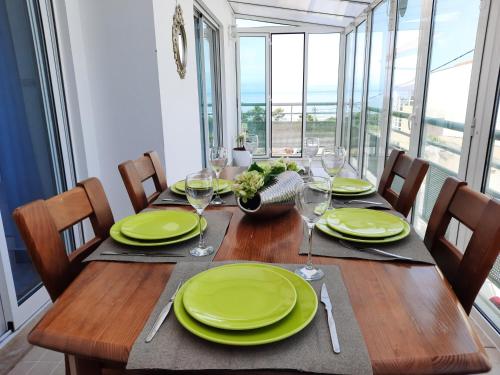 una mesa de comedor con platos verdes y copas de vino en Casa Celia, en Nazaré