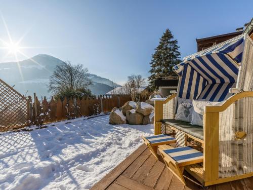 a snowy backyard with a bench and a fence at Chalet Weinberg Top 1 & Top 2 by Apartment Managers in Kirchberg in Tirol