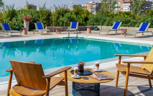 a table and chairs next to a swimming pool at Ibis Styles Madrid City Las Ventas in Madrid