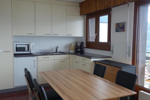 a kitchen with a wooden table and a table and chairs at Remointze COSY & CENTER apartments by Alpvision Résidences in Veysonnaz