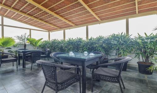 a patio with tables and chairs and potted plants at Treebo Premium Raj Vista Global Village in Bengaluru