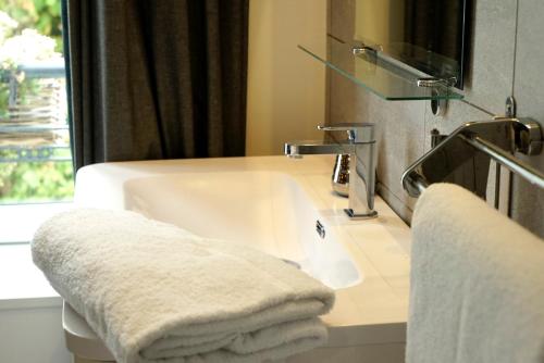 a bathroom with a sink and a mirror and towels at La Villa des Sables in Concarneau