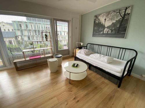 een slaapkamer met een bed, een tafel en 2 ramen bij Studio Morgane-balcon couvert-wifi-près centre-linge et ménage in Reims