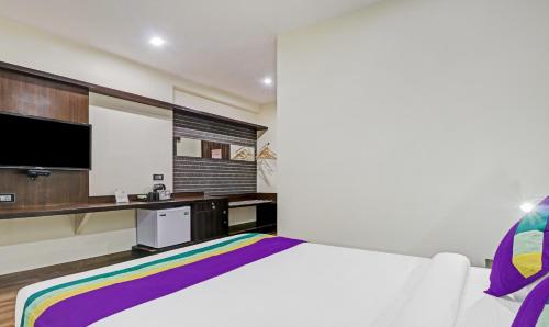 a bedroom with a white bed and a tv at Treebo Premium Raj Vista Global Village in Bengaluru