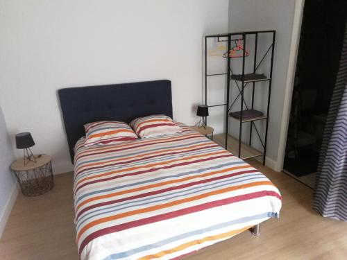- une chambre avec un lit et une couverture rayée colorée dans l'établissement SAMANKE lOUNGE, à Floirac