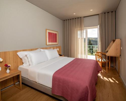 a hotel room with a bed and a window at Montebelo Principe Perfeito Viseu Garden Hotel in Viseu