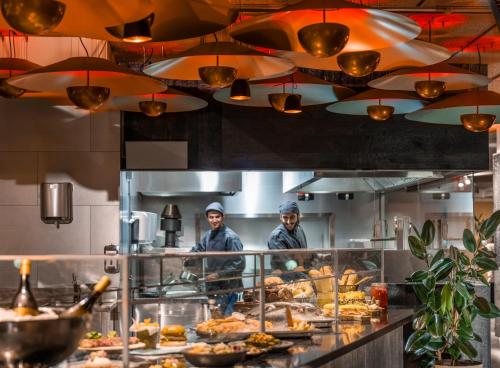 two men standing in a kitchen preparing food at Ibis Styles Madrid City Las Ventas in Madrid