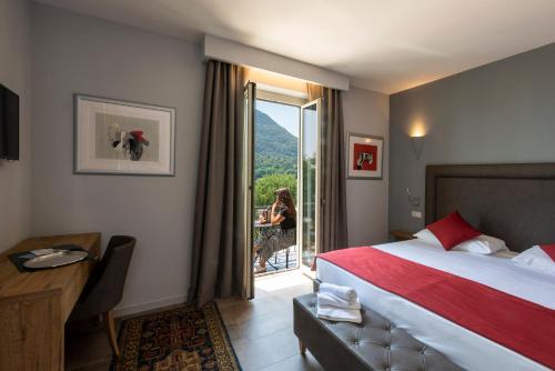 a hotel room with a bed and a woman sitting at a table at Hotel Ristorante La Quartina in Mergozzo