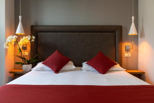a bed with two red pillows in a bedroom at Hotel Ristorante La Quartina in Mergozzo
