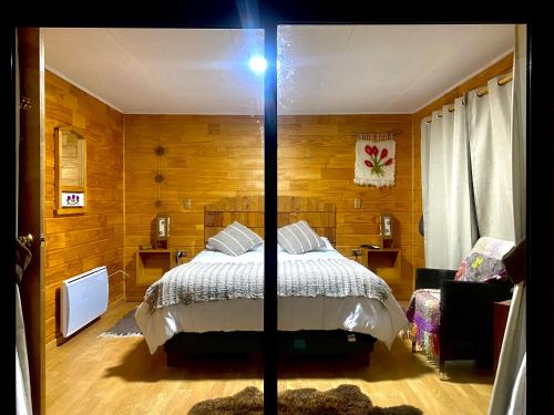 a bedroom with a bed in a room with wooden walls at El Reflejo Lodge Spa - Queilen - Chiloé in Queilén