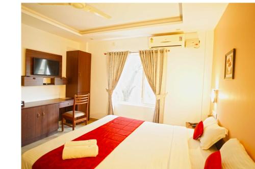 a bedroom with a bed and a desk and a television at North Centre in Cochin