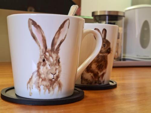 two coffee mugs with a painting of a rabbit on them at Rutland Rooms in Oakham