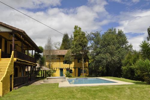 a house with a swimming pool in the yard at Hostería Colibri Aeropuerto in Tababela