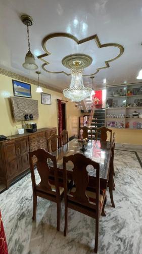 a dining room with a table and chairs and a chandelier at Dilaram Guest House in Srinagar