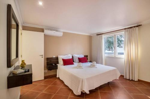 a bedroom with a bed with red pillows and a window at Apartamento Malick - Balaia in Albufeira