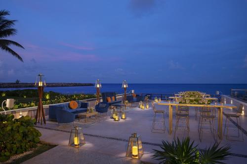 a patio with tables and chairs and the ocean at night at Dreams Jade Resort & Spa - All Inclusive in Puerto Morelos