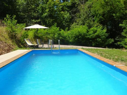 een blauw zwembad met een tafel en een parasol bij la Bergerie du Bois Joannin 1497 route des fleuriats in Iguerande