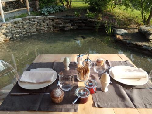 a picnic table with plates and glasses and a pond at Agriturismo Verdecrudo in Caldonazzo