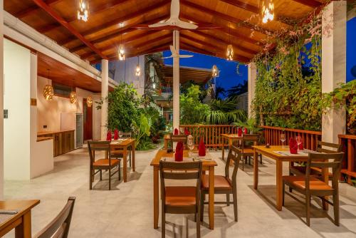 un restaurant avec des tables en bois, des chaises et des plantes dans l'établissement Ithaa Dhigurah, à Dhigurah