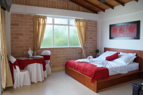 a bedroom with a bed and a table and a window at Hostería Fundadores in Santa Fe de Antioquia