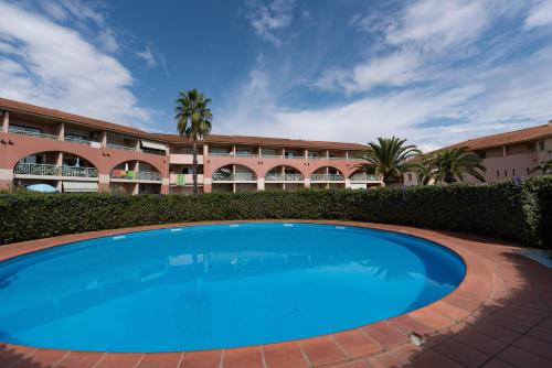 une grande piscine bleue devant un immeuble dans l'établissement Arinella, à San-Nicolao