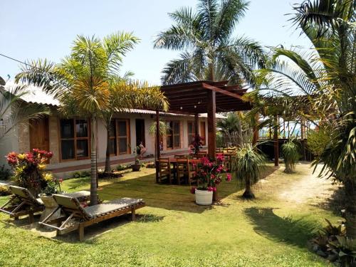 um resort com uma mesa, cadeiras e palmeiras em Cucube em Ayangue