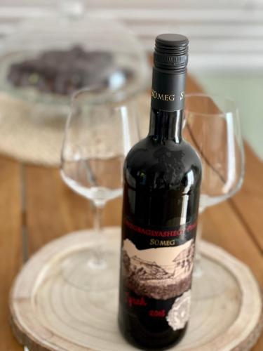 a bottle of wine on a plate next to a glass at Szőlőhegy Vendégház Sümeg in Sümeg