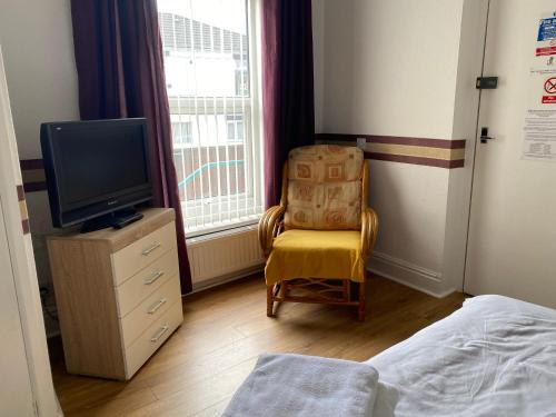 Schlafzimmer mit einem Bett, einem TV und einem Stuhl in der Unterkunft Park View Hotel and Guest House in Thatto Heath